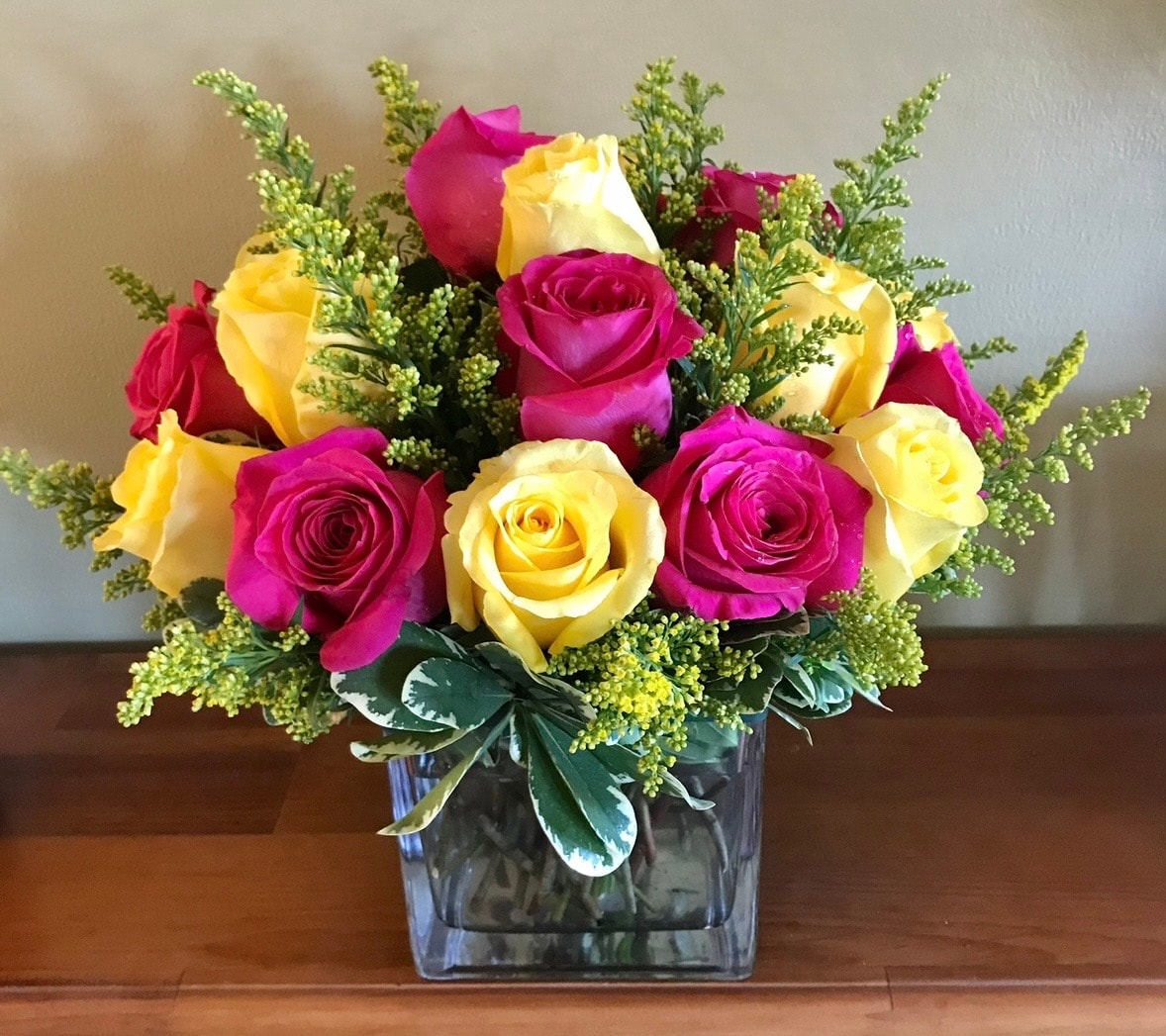 Everyday floral arrangement with magenta and yellow roses in glass vase