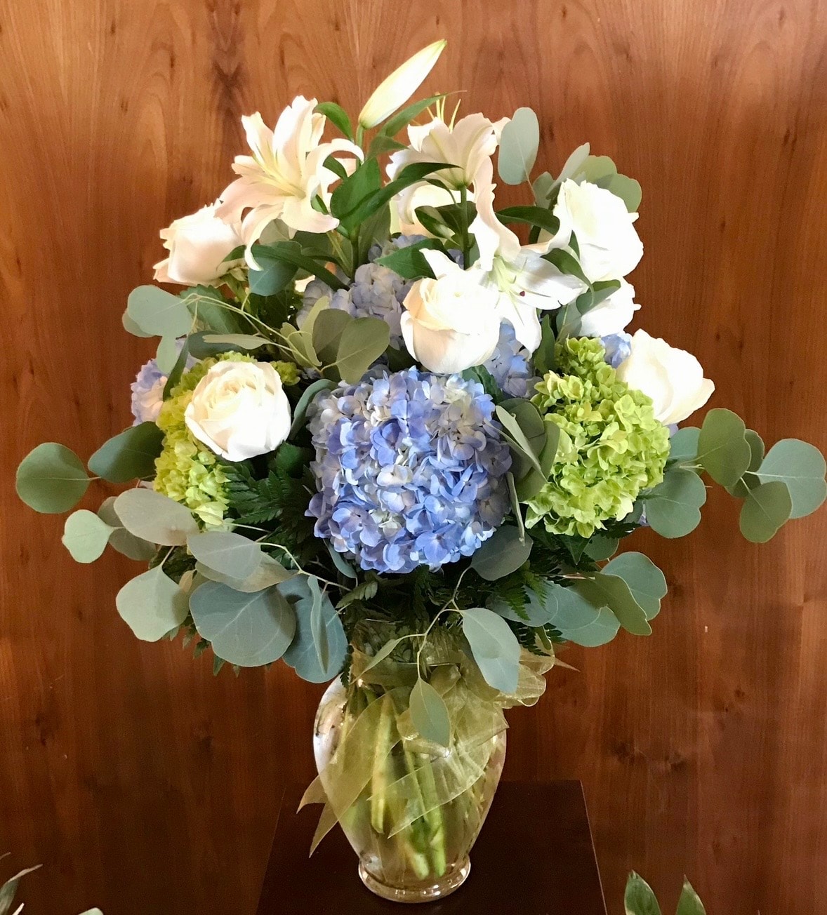 Everyday floral arrangement with white roses, blue hydrangeas, green chrysanthemums and eucalyptus