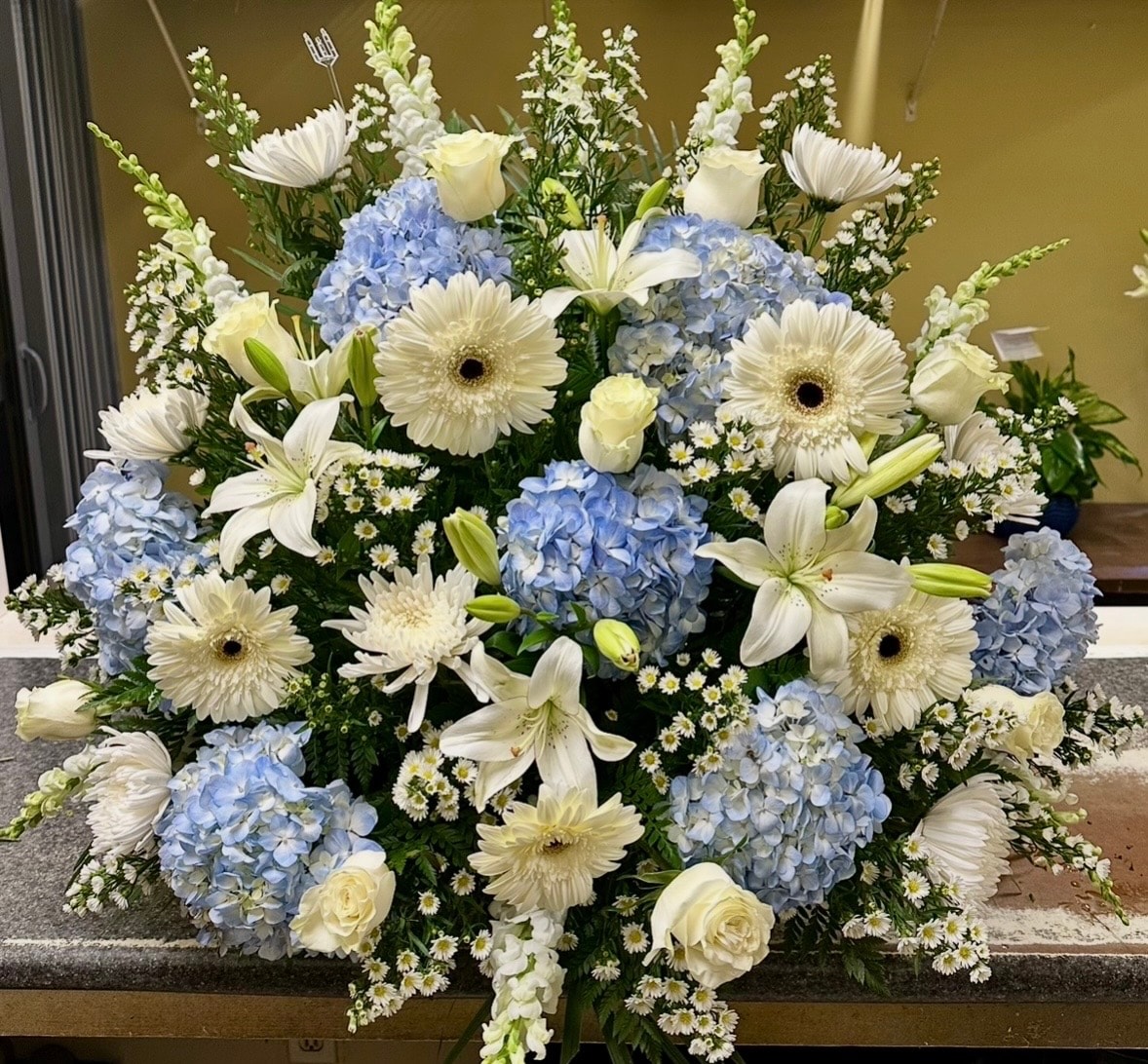 White gerbera blue hydrangea lily funeral arrangement